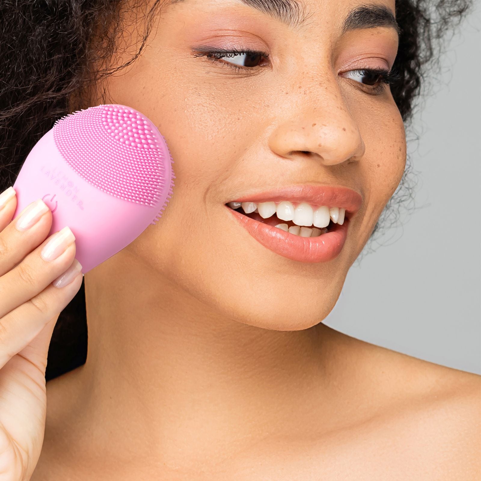 Woman using a facial cleansing brush on her cheek