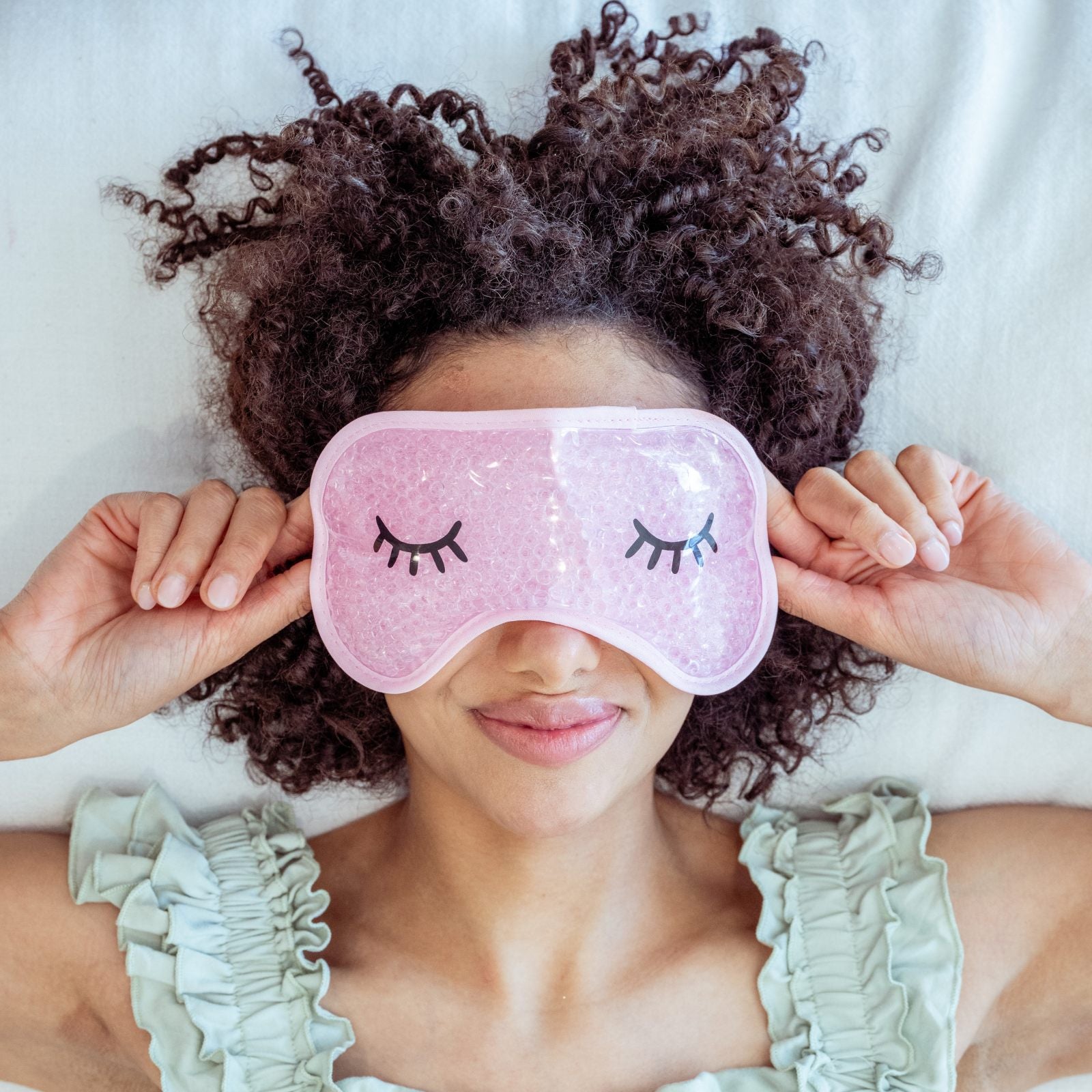 Woman wearing a pink cooling gel eye mask while relaxing